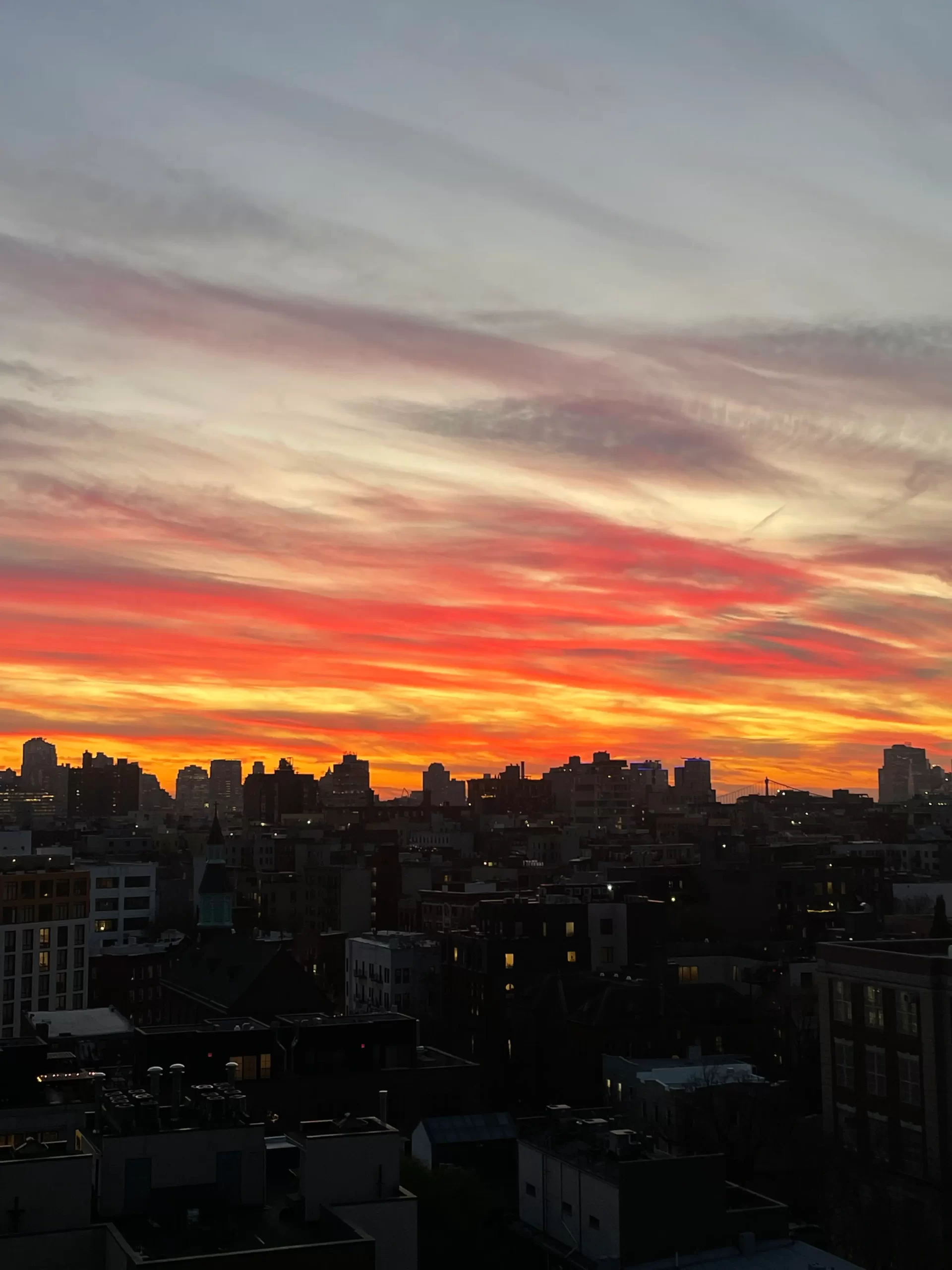 City skyline at sunset with orange and pink streaked sky.